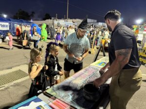 People analyzing topographic map of project area at public response event. Taking place in the City of Buckeye at Halloween event.
