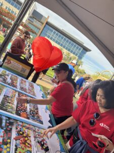 People participating in public response activity by placing dots on pictures representing areas of interest related to project. Taking place in City of Goodyear at Heart Health event.