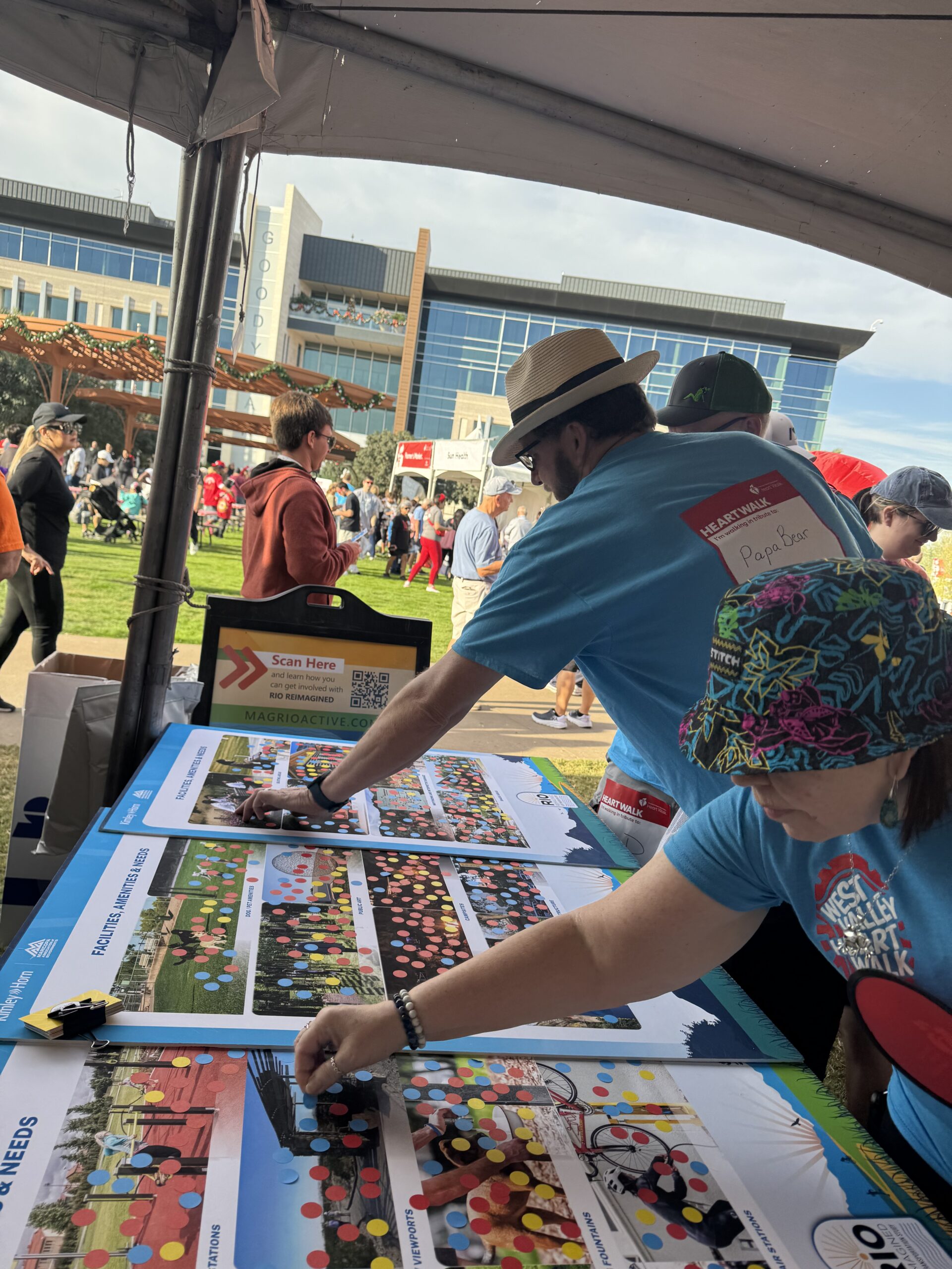 People participating in public response activity by placing dots on pictures representing different areas of interest related to project. Event taking place in City of Goodyear at Heart Health event.
