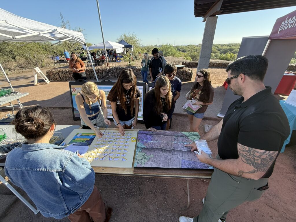 People observing topographic map of project area and participating in rubber band activity at public outreach event. Taking place at Phoenix Nature Festival.