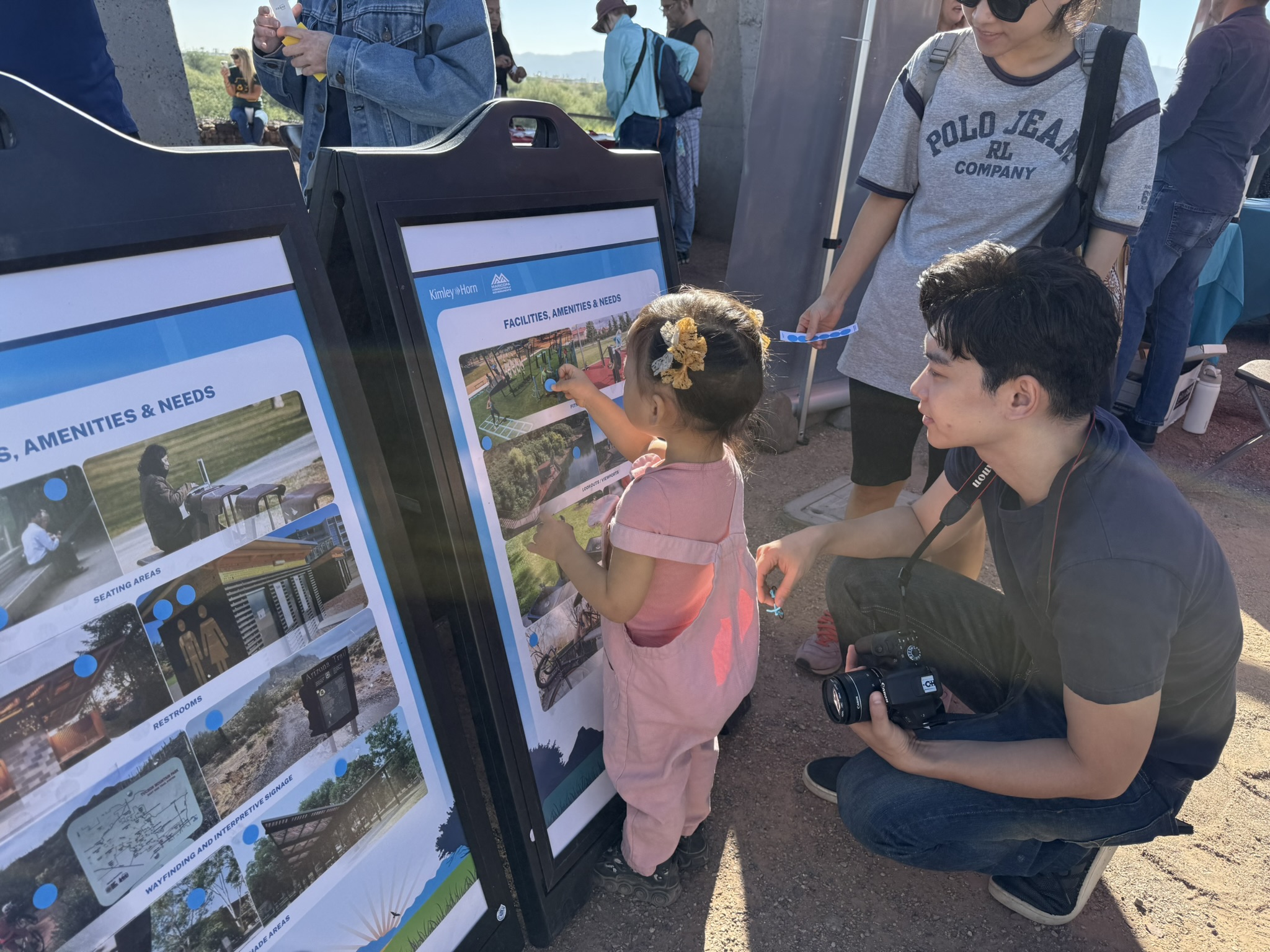 Young girl participating in public response activity by placing dot on picture that represents areas of interest related to the project.