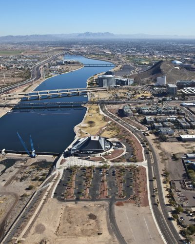 Aerial view of an urban river corridor featuring a series of interconnected lakes, bridges, roadways, and surrounding development. The waterway extends through a highly developed area with office buildings, residential neighborhoods, recreational amenities, and transportation infrastructure.